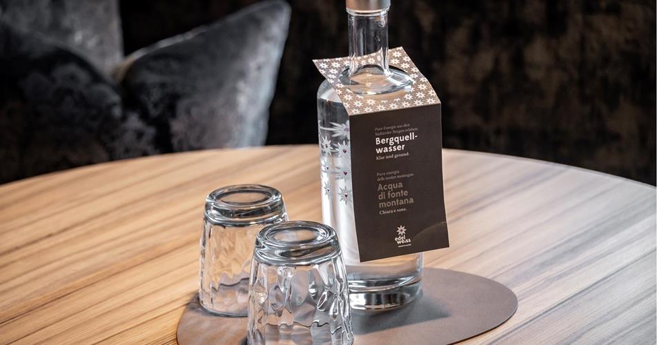 Mountain spring water bottle with two glasses on a wooden table