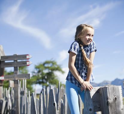 A girl is sitting on a wooden fence