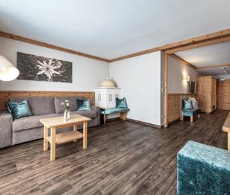 Der Wohnbereich der Suite Edelweiss mit Sofa und Kachelofen