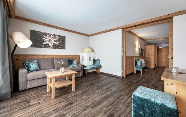 The living area of the Suite Edelweiss with couch and tiled stove