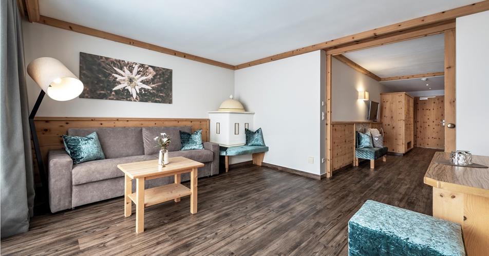 The living area of the Suite Edelweiss with couch and tiled stove