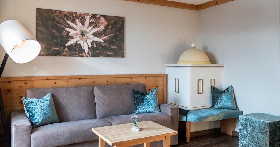 The living area of the Suite Edelweiss with couch and tiled stove