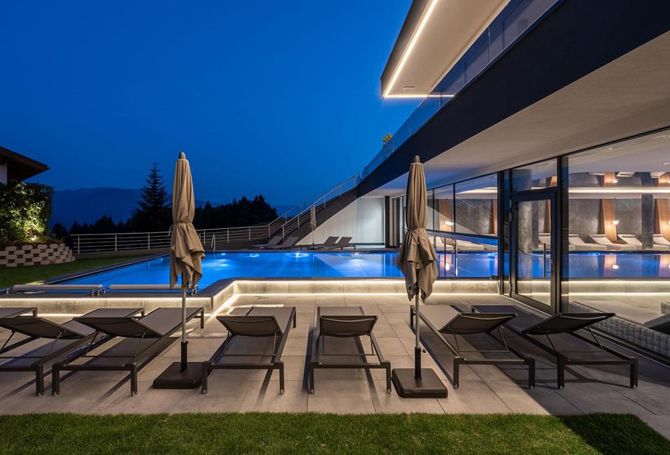 The indoor and outdoor pool with loungers in the evening