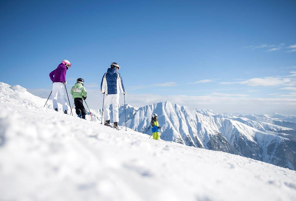 Eine Familie genießt die Aussicht auf die Berge beim Skifahren