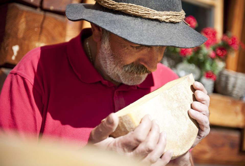 An alpine dairy farmer with one half of a cheese wheel
