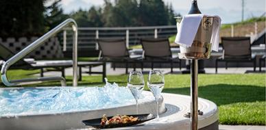Outdoor whirlpool with bubbling water, two glasses of sparkling wine, fruit plate, and champagne cooler.