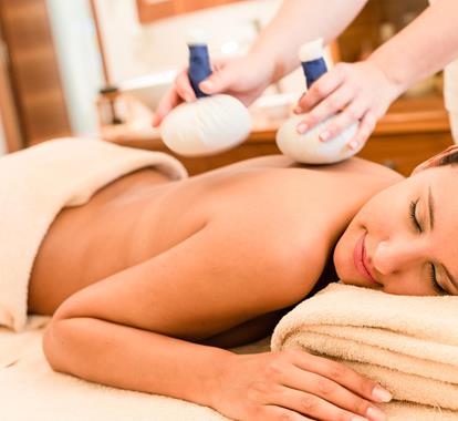 A woman is getting a massage with herbal compresses