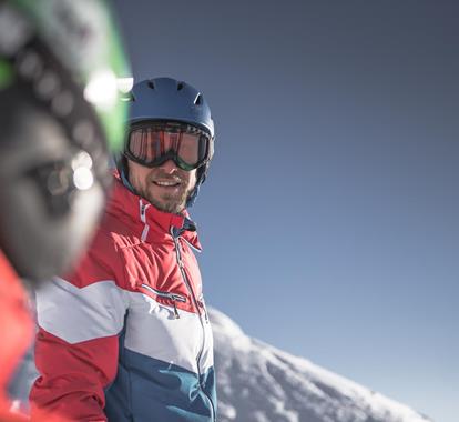 Sciatore con casco e occhiali da sci sotto cielo limpido